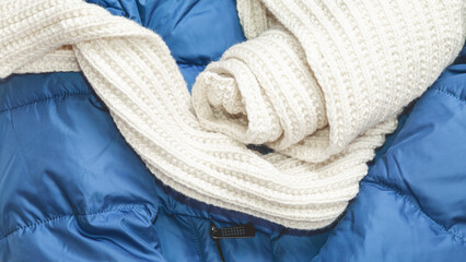 Fototapeta na wymiar warm winter knit scarf on blue jacket. Fashionable warm winter background. Blue Down jacket with fur collar hood.