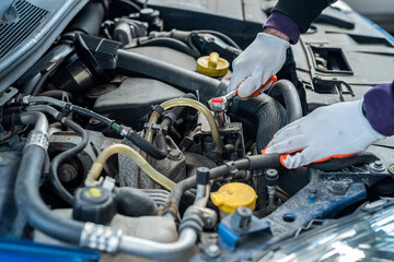 close up of mechanic hands hold key for repair of the car in open hood