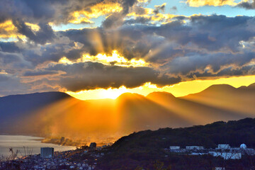 夕陽が山並みにオレンジ色の光を放射する景色