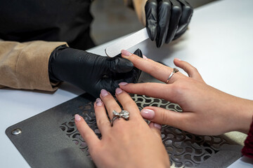 a manicurist in special gloves saws off a new client's nails during an epidemic. - obrazy, fototapety, plakaty