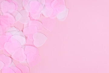 White and pink heart shaped paper confetti on pink background with copy space