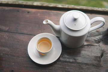 cup of hot tea with white ceramic tea pot on natural brown wood table top view with copy space  