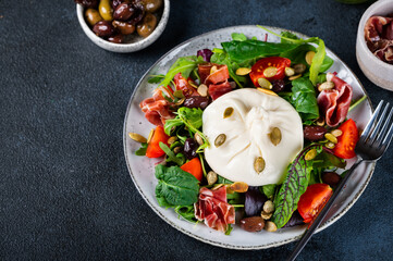 Burrata, Italian fresh cheese made from cream and milk of buffalo or cow. Burrata salad with tomatoes and salad mix. Healthy eating concept. Keto diet salad.