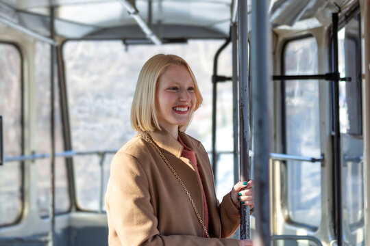 One Young Woman Smiling in a Bus While looking through the window Beautiful Young Woman Taking Bus to Work. Passenger in the Bus or Train, Technology Lifestyle, Transportation and Traveling Concept.
