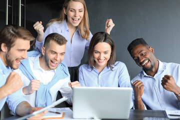 Happy business people laugh near laptop in the office. Successful team coworkers joke and have fun together at work.