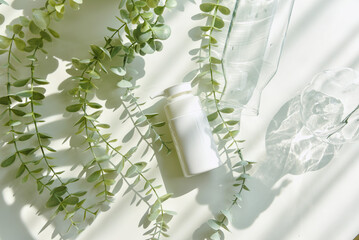 Cosmetic bottle containers packaging with green herbal leaves in shadow and light effect, Blank...