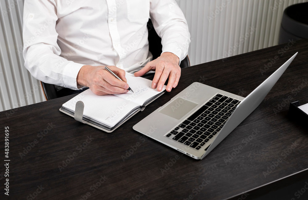 Poster Man taking notes in planner. Businessman sitting at desk and working or studying on laptop. Online education or using computer technology in work concept. High quality photo