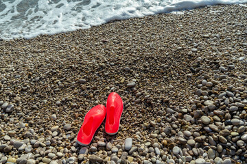 Protective rubber slippers of pink color for walking on stones and corals. Sea pebble beach