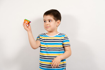 A 4-year-old boy in a striped T-shirt holds the triangles of a magnetic constructor on a white background