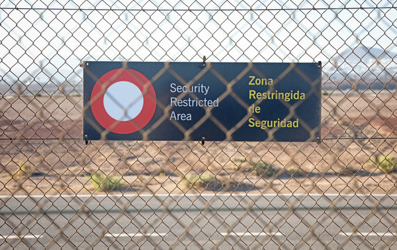 Security restricted area sign on a fence at an airport