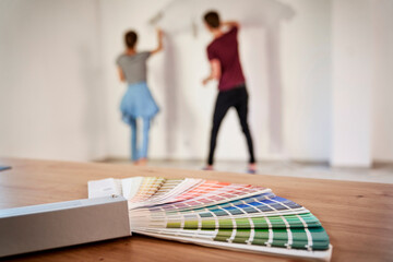 Blurred couple in the background painting wall in the house