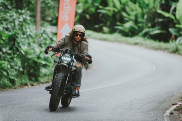 Mooi meisje dat plezier heeft met het besturen van haar aangepaste café racer-motorfiets