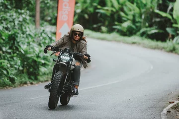Fototapete Motorrad Schönes Mädchen, das Spaß daran hat, ihr benutzerdefiniertes Cafe Racer-Motorrad zu fahren