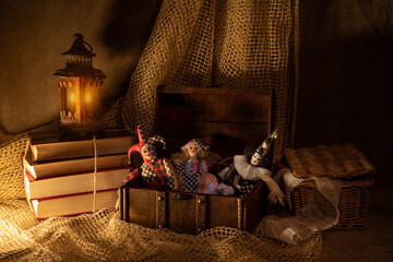Doll figurines of Harlequin, Columbine and Pierrot in an open chest