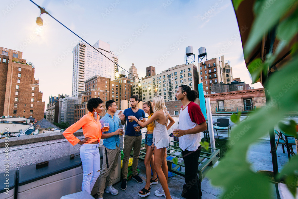 Wall mural Young happy people having a barbecue dinner on a rooftop in New York.  Group of friends having party and having fun