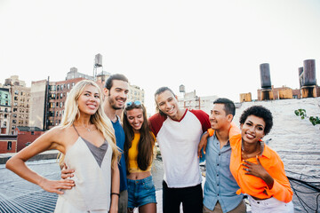 Young happy people having a barbecue dinner on a rooftop in New York.  Group of friends having...
