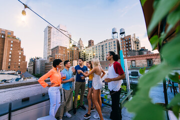 Young happy people having a barbecue dinner on a rooftop in New York.  Group of friends having party and having fun