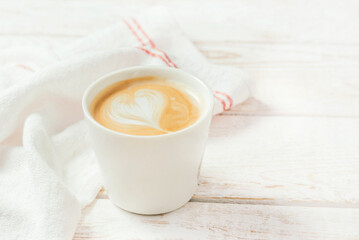 White cup of the coffee and vintage cloth
on light rustic wooden background