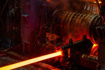 The red-hot metal bar is rolled on a rolling mill