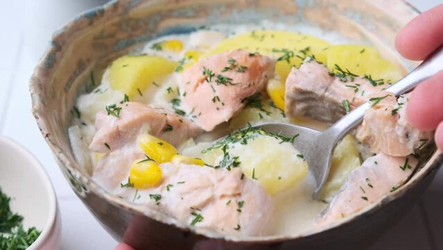 Norwegian fish soup with trout, potatoes and corn, gray background. Salmon and potato chowder.