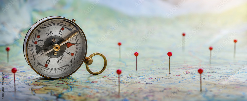 Poster magnetic compass and location marking with a pin on routes on world map. adventure, discovery, navig