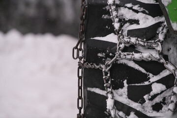 Wheel of a truck with snow chains mounted on it for a better grip in winter roads