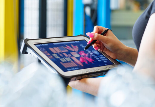 Woman using tablet PC with digitized pen in industry