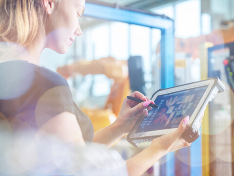 Woman using tablet PC with and digitized pen in industry