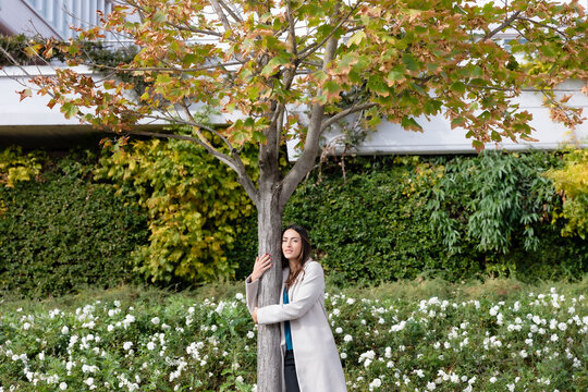 Businesswoman embracing tree in autumn park