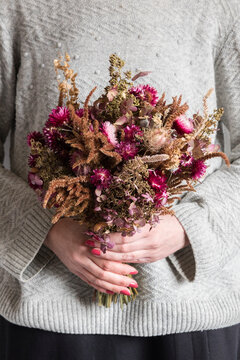 Mid section of woman holding bouquet of various dried flowers