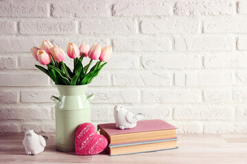 Bouquet of pink tulips with books, birds and heart on the white brick wall.