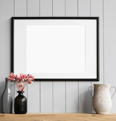 Blank picture frame mockup on white wall. Template for painting or poster. Living room interior design. View of modern rustic style interior with artwork mock-up