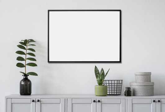 	
Blank picture frame mockup on white wall. Template for painting or poster. White living room interior design. View of modern rustic style interior with artwork mock-up
