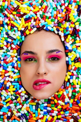 Artistic image of a beautiful woman sunk inside colored pills and capsules.