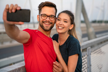 Fitness, sport, training, technology and lifestyle concept. Two smiling people with smartphones outdoors