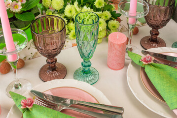 Romantic spring table setting for two with wine glasses, candles and flowers
