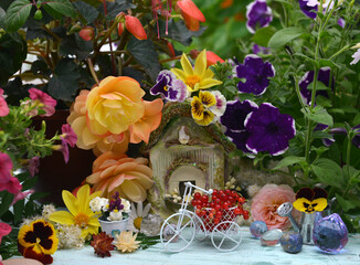 Lovely summer still life with tiny bicycle, doll house, flowers and berries in the garden.