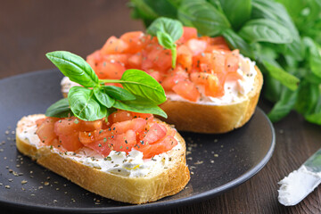 Tasty savory tomato Italian appetizers, or bruschetta, on slices of toasted baguette garnished with basil