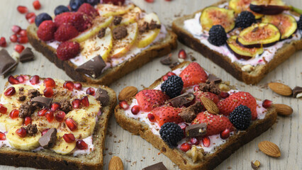 Toasts for a healthy breakfast, banana, cream cheese, figs, blackberries, banana, pomegranate, strawberries. Top view