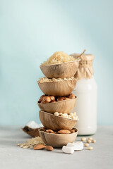 Rice, oat, almond, hazelnut and soy beans in natural palm leaf bowls and bottle of milk on the...