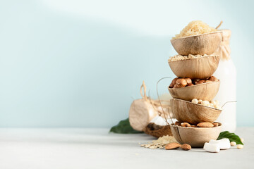 Rice, oat, almond, hazelnut and soy beans in natural palm leaf bowls and milk bottles on the table, Ingredients for making Dairy free milk substitute drinks