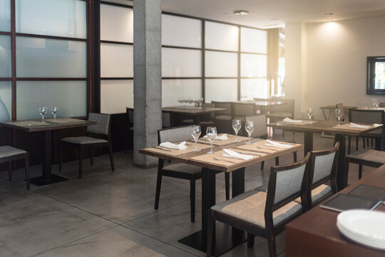 Chairs and tables with glasses arranged in empty restaurant