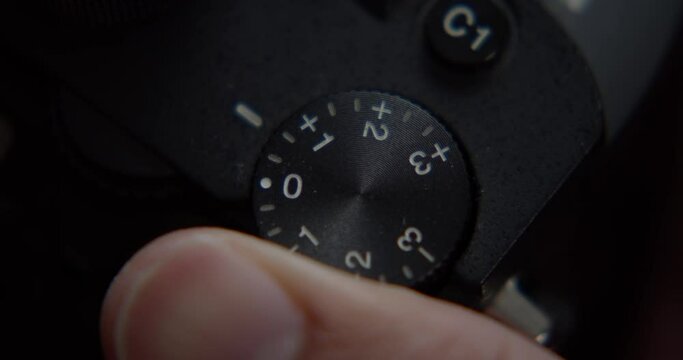 Turning exposure dial on digital camera, close up top down view