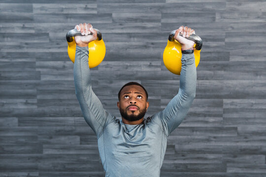 Determined athlete lifting kettlebell in front of wall