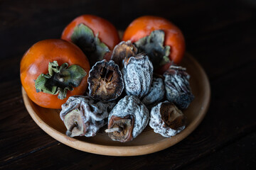 Dried persimmon and fresh persimmon on a wooden background. Healthy diet. Healthy diet