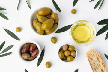 Small bowl with olive oil and olives on white background, top view