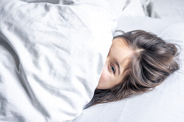 A cute little girl lies in bed and doesn't want to get up.