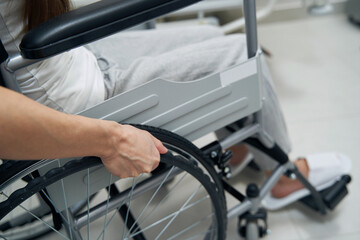 Person with disability propelling wheeled chair in hospital ward