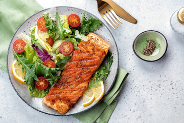 Grilled salmon fish fillet and fresh green lettuce vegetable tomato salad