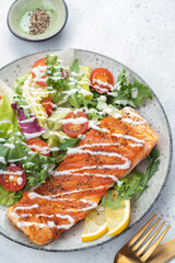 Grilled salmon fish fillet and fresh green lettuce vegetable tomato salad